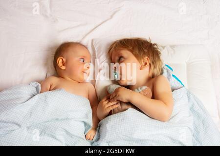 Boy look at little baby sister laying in the bed Stock Photo