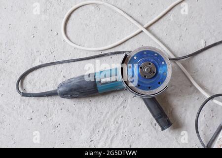 The machine for angle grinding lies after working with building materials on the concrete floor, Stock Photo