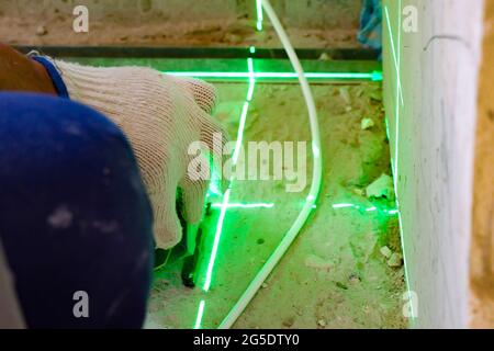 the builder measures the repair lines using a green laser level, Stock Photo