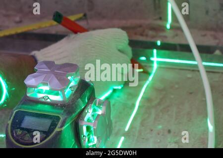 the builder measures the repair lines using a green laser level, Stock Photo