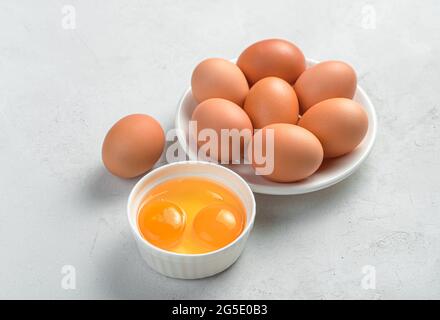 Chicken eggs in a plate and egg yolks on a light background. Side view, space for copying. Stock Photo