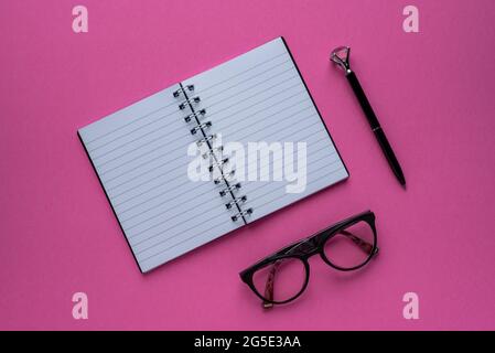 Photography of notebook, glasses, pen, pink background Stock Photo