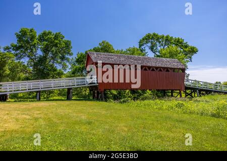 An old red wooden covered bridge in rural Iowa. Stock Photo