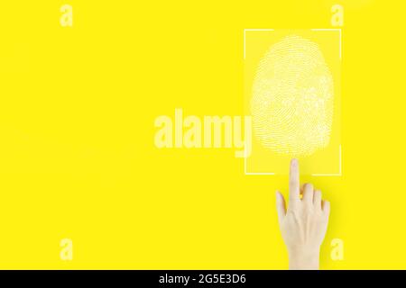 Password control through fingerprints. Young woman's hand finger pointing with hologram Fingerprint scan on yellow background. Immersive technology fu Stock Photo