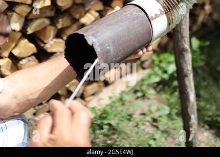 Close up of man hand cleaning chimney pipe outside with tool. Cleaning a wood burning stove concept. Chimney sweep cleaning Stock Photo