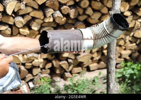 Man hand cleaning chimney pipe outside with tool. Cleaning a wood burning stove concept. Chimney sweep cleaning Stock Photo