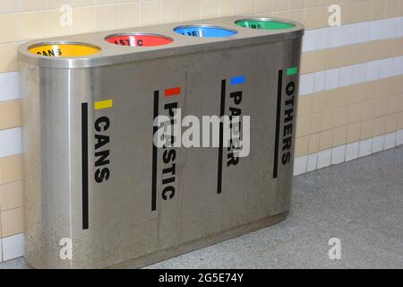 A metal trash bin for different garbage with an inscription in English (Cans, Plastic, Paper and Others), Separation and sorting of rubbish Stock Photo