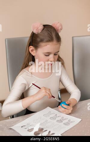 A girl draws a pattern on a colored egg. Home preparations for the Easter holiday Stock Photo