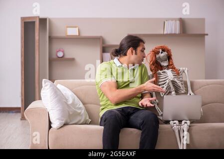 Man sitting on the sofa with female skeleton Stock Photo