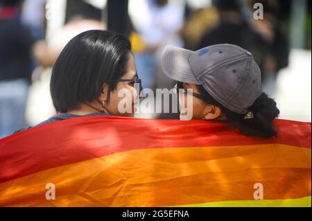 San Salvador, El Salvador. 26th June, 2021. Women look at each other while holding up a rainbow flag. Members of the LGBT community march to celebrate pride day months after the Salvadoran Congress archived various law's that would benefit the LGBT community. Credit: Camilo Freedman/ZUMA Wire/Alamy Live News Stock Photo