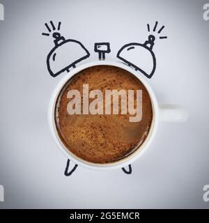 Cup of fresh hot coffee in the shape of an alarm clock on a white background, the concept of morning wake up. Stock Photo
