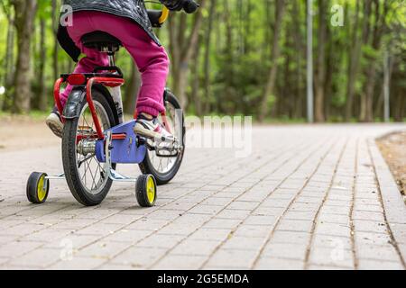 Close-up of a child rides a bicycle with three wheels. Stock Photo