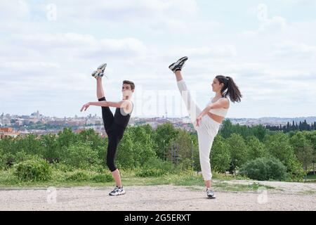 Young couple doing a high kick. Practicing street dance, ballet, dancing steps, movements at a park. Stock Photo