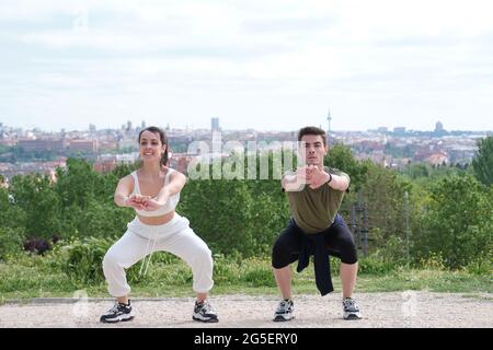 Two fit friends doing squats at a park. Sporty couple outside. Stock Photo