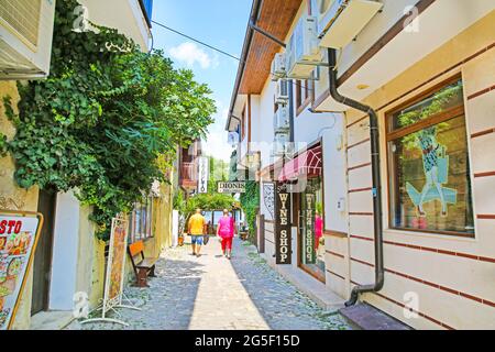 29 of July 2019, Nessebar Bulgaria. Narrow street with souvenir shop windows and tourists, bright color houses, summertime. Stock Photo