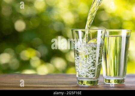 water pouring into glass on table outdoors Stock Photo