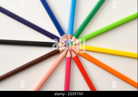Background detail with color pencils placed on circle on white table. Top view Stock Photo