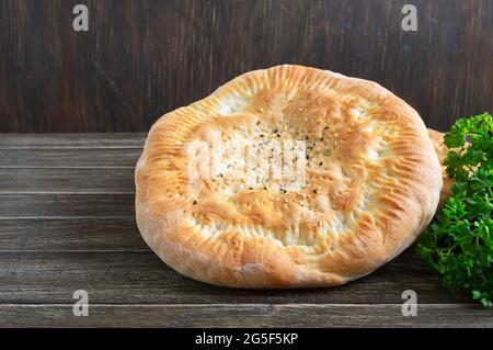 Traditional Asian simple bread. Freshly baked flatbread with sesame seeds on a wooden rustic background. Stock Photo