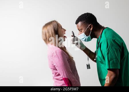 Doctor uses smartphone light to check patient's throat Stock Photo