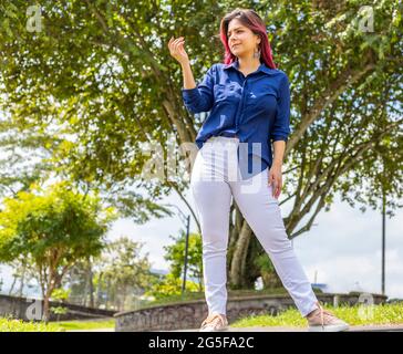 young latina woman standing in the park and looking at her right hand Stock Photo