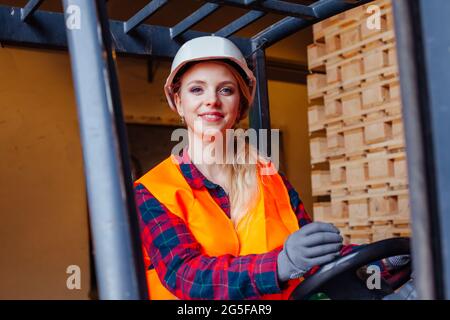 The young woman is driving a forklift in a warehouse Stock Photo