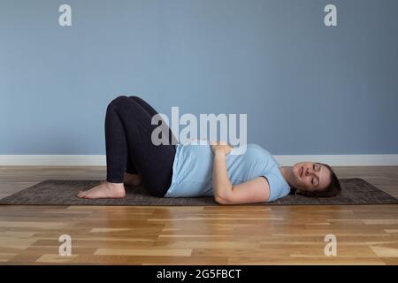 Pregnant woman lying in Shavasana, resting after practice, meditating Stock Photo