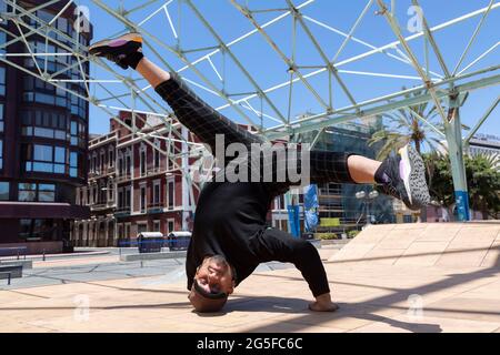 Young latin man urban acrobatic dancer on the street doing a performance. Stock Photo