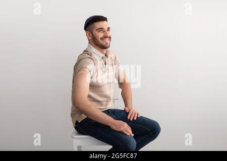 Inoculation Concept. Portrait Of Cheerful Smiling Jewish Male Patient Showing Vaccinated Arm With Sticking Patch On His Shoulder After Coronavirus Vac Stock Photo