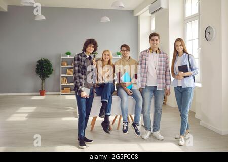 Portrait of teenage classmates with books and gadgets in high school hallway Stock Photo