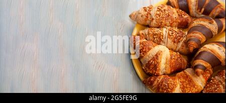Food banner. Croissants on a plate top view. Place for your text. Fresh pastries on a plate. Bakery. Chocolate croissant and walnut croissant for breakfast. Stock Photo