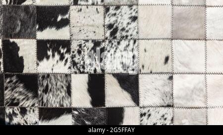 Cattle animal skin hides  closeup photo image abstract background  detail of cleaned treated stiched together black white fur square blocks to make ru Stock Photo