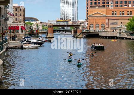 MILWAUKEE, WI,USA - JUNE 19, 2021 - Unidentified individuals kayaking and boating on the Milwaukee River in downtown Milwaukee's Riverwalk. Stock Photo