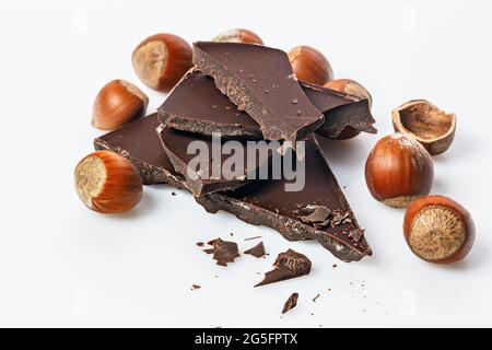 Ripe wild hazelnuts and bitter chocolate. Nuts and and stack of a dark chocolate on a white background. Natural organic products. Copy space. Food sti Stock Photo