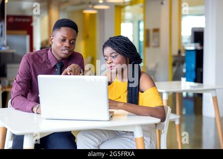Portrait of two black students with netbook sitting at home interior, african american using laptop computer for searching information and making book Stock Photo