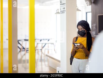Two african students with mask using their mobile phones on campus Stock Photo