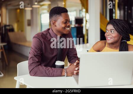 Portrait of two black students with netbook sitting at home interior, african american using laptop computer for searching information and making book Stock Photo