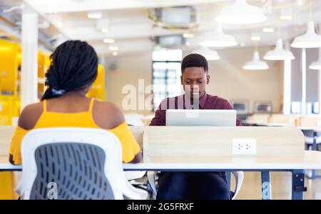 Portrait of two black students with netbook sitting at home interior, african american using laptop computer for searching information and making book Stock Photo