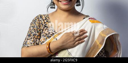 Isolated on white background an Indian female in saree touching her heart with smiling face on white background Stock Photo