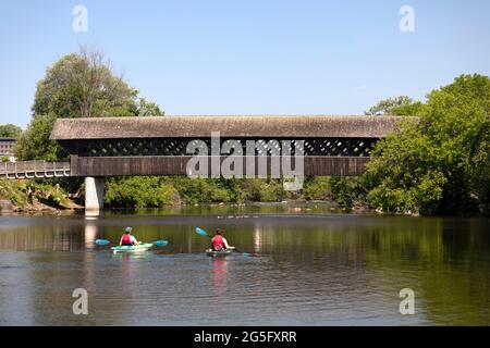 The all wood lattice covered pedestrian & cyclist covered bridge with two kayakers. Guelph Ontario Canada. Stock Photo