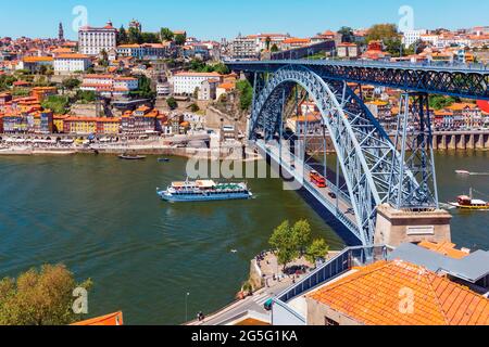 Porto, Porto District, Portugal. An excursion boat by the Dom Luis I bridge which crosses the Douro river and links Vila Nova de Gaia, bottom, and Por Stock Photo
