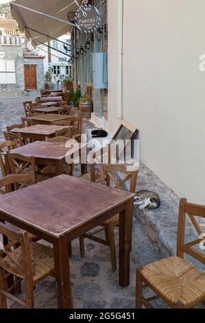 HYDRA PORT, HYDRA ISLAND, GREECE - AUGUST 27 2018 : Tables of taverna in Hydra Port. Stock Photo