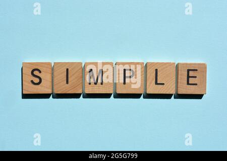 Simple, word in wooden alphabet letters isolated on plain blue background Stock Photo