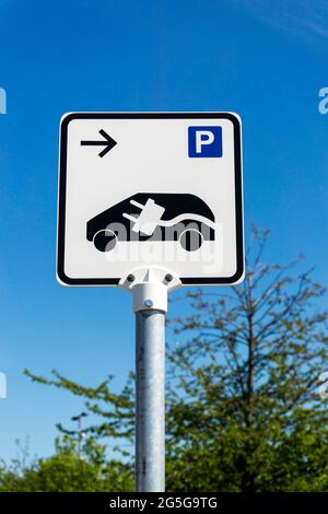 Sign to an Electric Vehicle charging point in a car park with P sign and car charging icon. Stock Photo