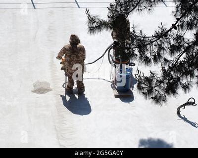 Workers in overalls remove construction dust from a concrete pavement in sunlit area with an industrial vacuum cleaner. Street renovation Stock Photo