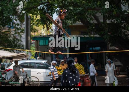 New Delhi, India. 27th June, 2021. An unidentified Indian girl does street acrobatics by walking on a rope in a performance to earn a livelihood. Credit: SOPA Images Limited/Alamy Live News Stock Photo