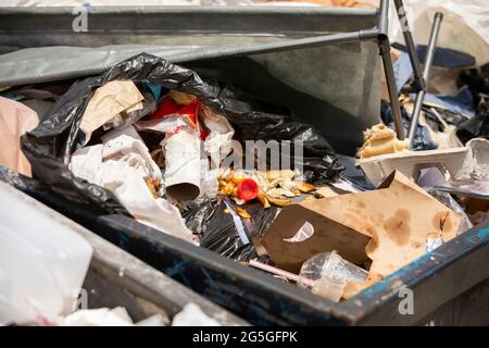 Daytime view of rotting food and other plastic waste and refuse in a dumpster. Stock Photo