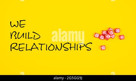 A yellow background with "we build relationships" text and dice Stock Photo