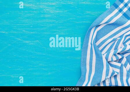 A blue and white napkin on the right side of a light blue wooden table, top view Stock Photo