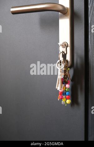 keys with keychain in the lock of black front door. Close up Stock Photo