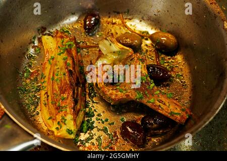 grilled artichoke and fennel in a hot pan with olives and capers, mediterranean style vegetables Stock Photo